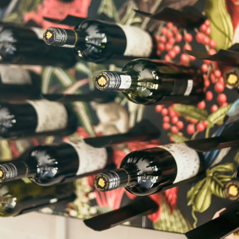 Wine bottles arranged on a reflective surface with a floral background
