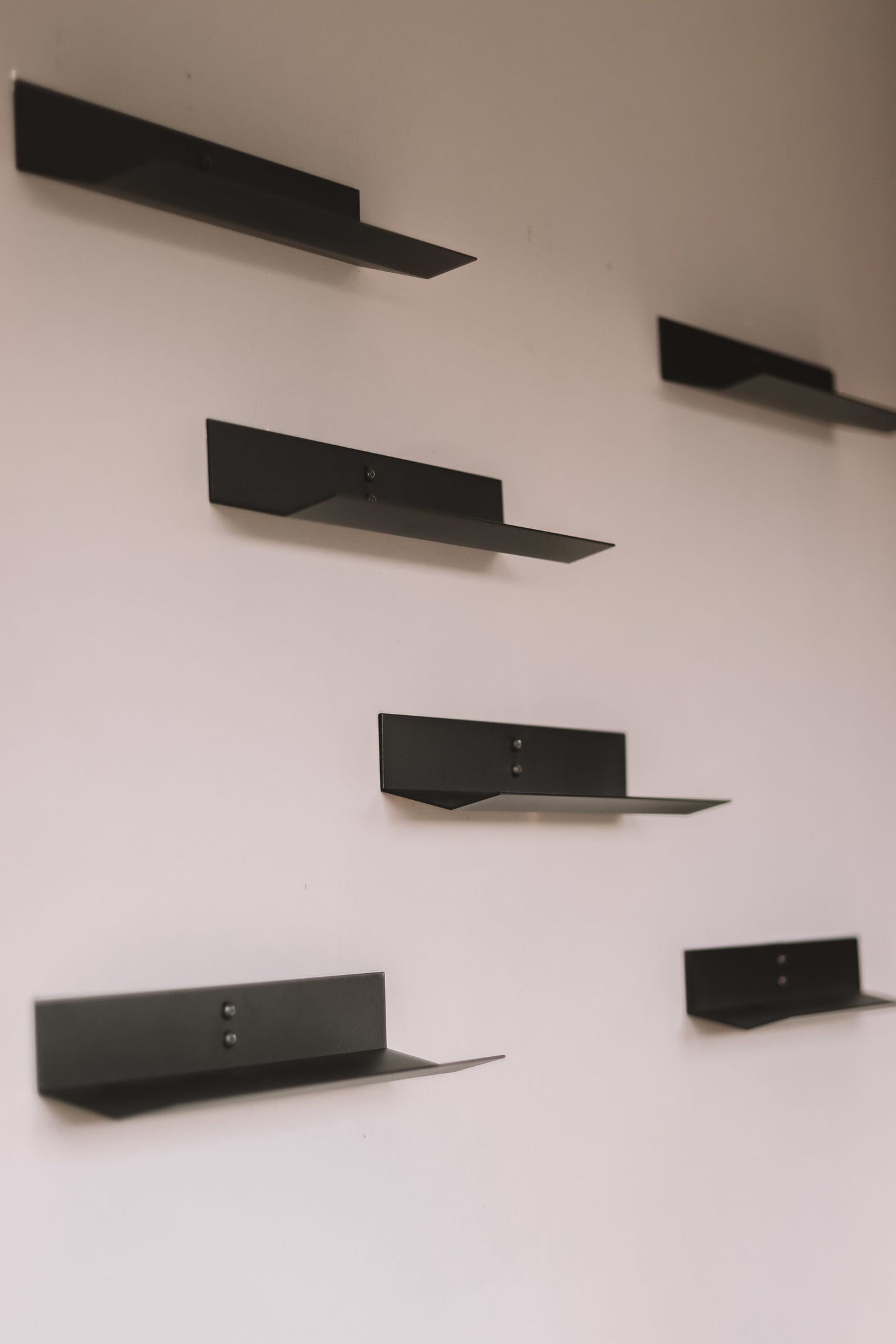 Set of black wine bottle shelves on a white wall
