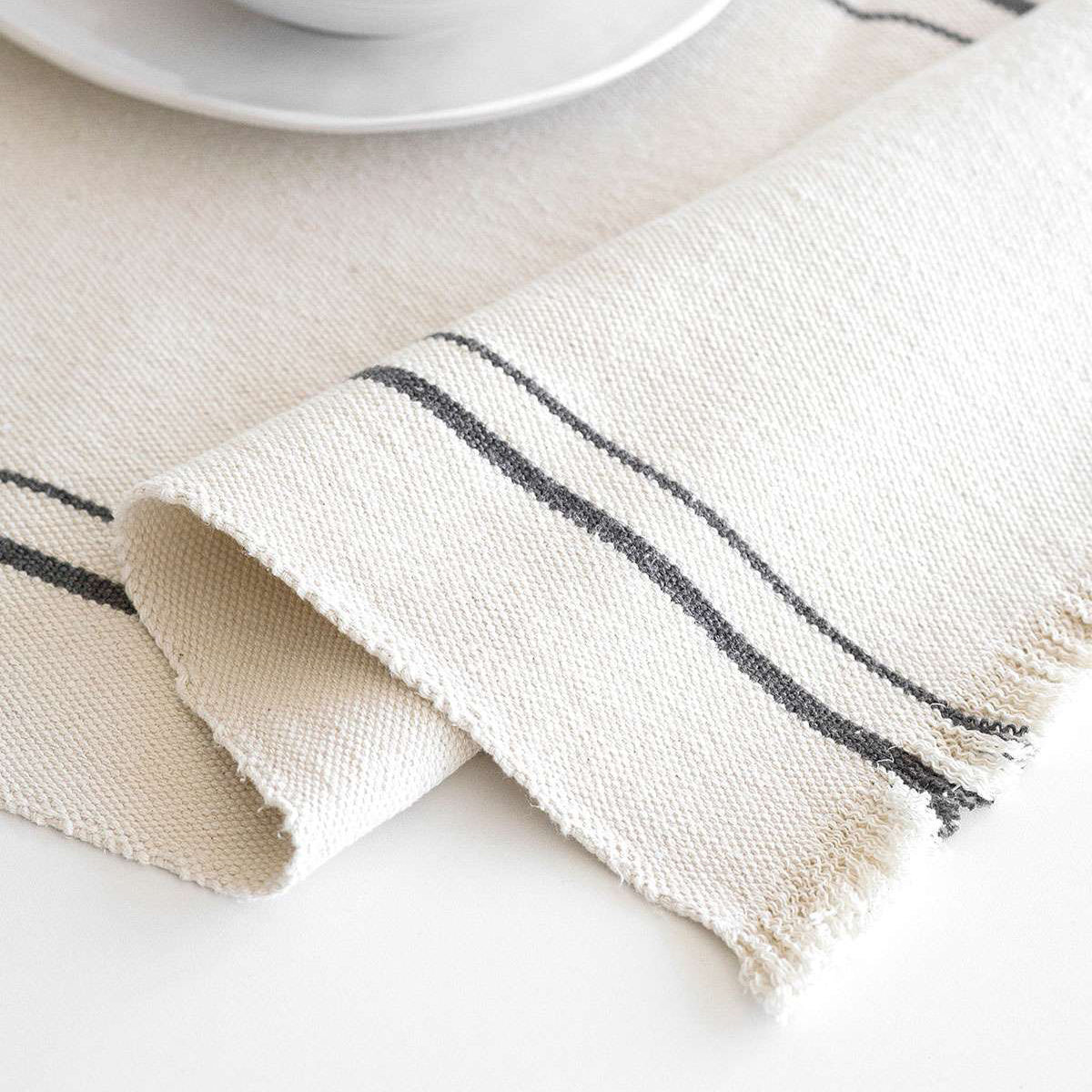 Beige woven tablecloth with dark grey lines on a white surface