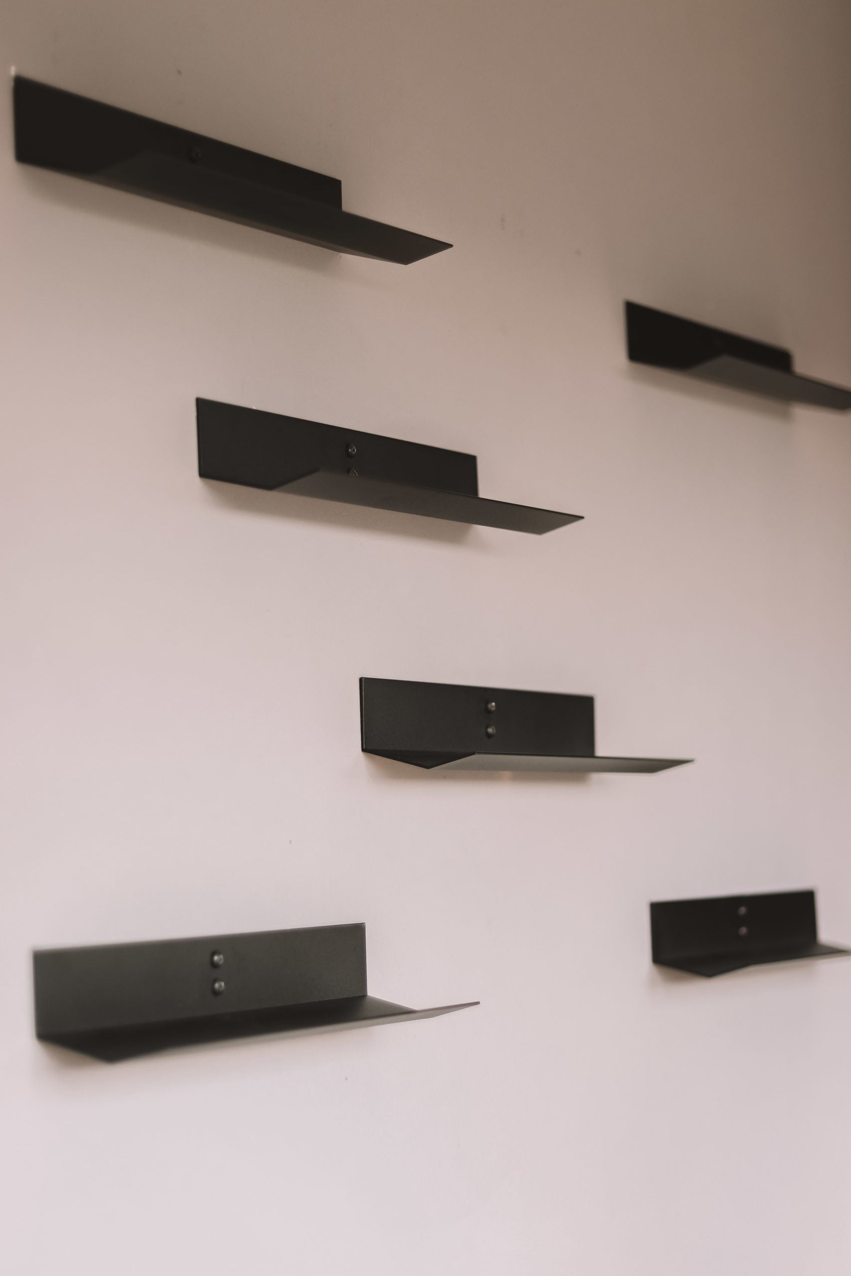 Set of black wine bottle shelves on a white wall