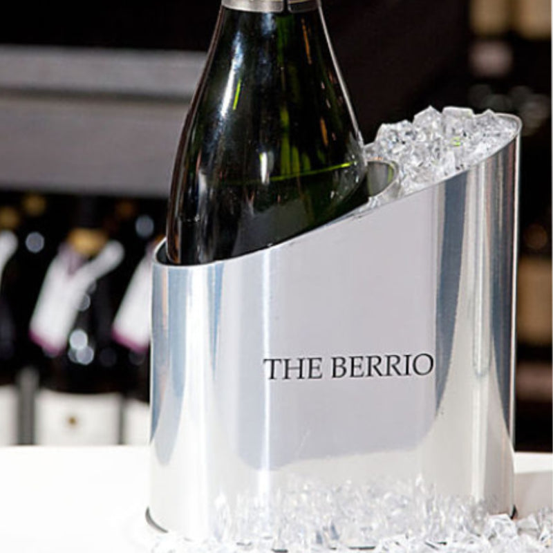 Silver wine cooler with a bottle of wine inside, branded 'The Berrio', on a blurred background.