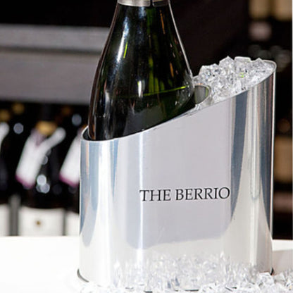 Silver wine cooler with a bottle of wine inside, branded 'The Berrio', on a blurred background.