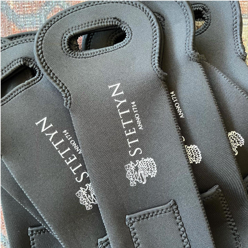 Black neoprene wine bags with Stettyn branding on a textured surface