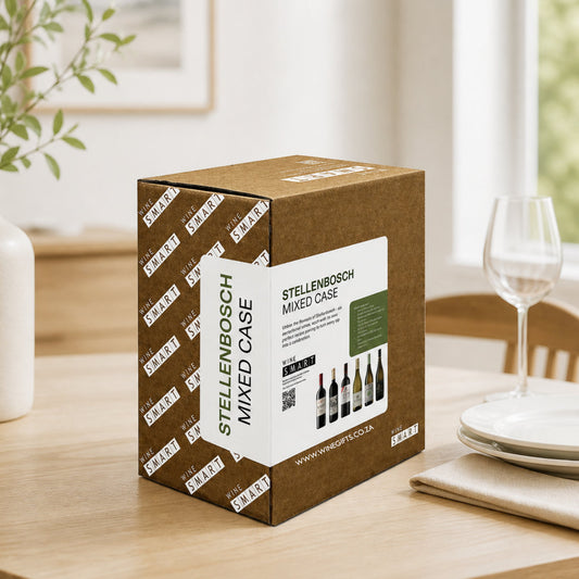 Wine box labeled 'Stellenbosch Mixed Case' on a table with wine glasses and plates in the background.